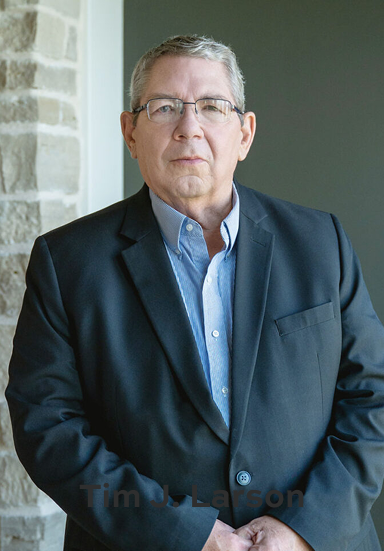 Tim J. Larson - Estate Planning Attorney Profile Professional portrait of attorney Tim J. Larson wearing glasses, a light blue dress shirt, and a dark blazer.